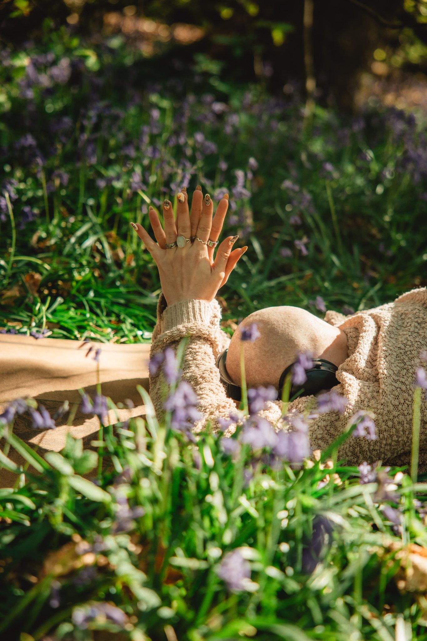 bald woman in grass, hands in prayer, close to earth, in the sun