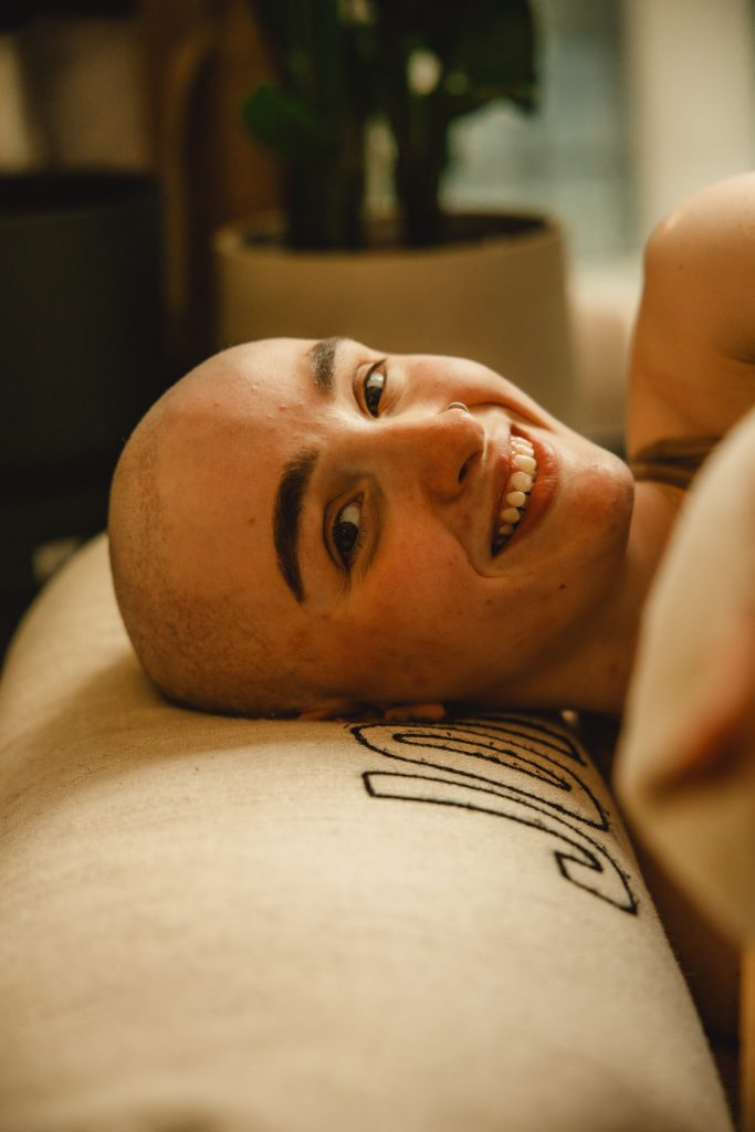 bald woman smiling laying on a yoga bolster