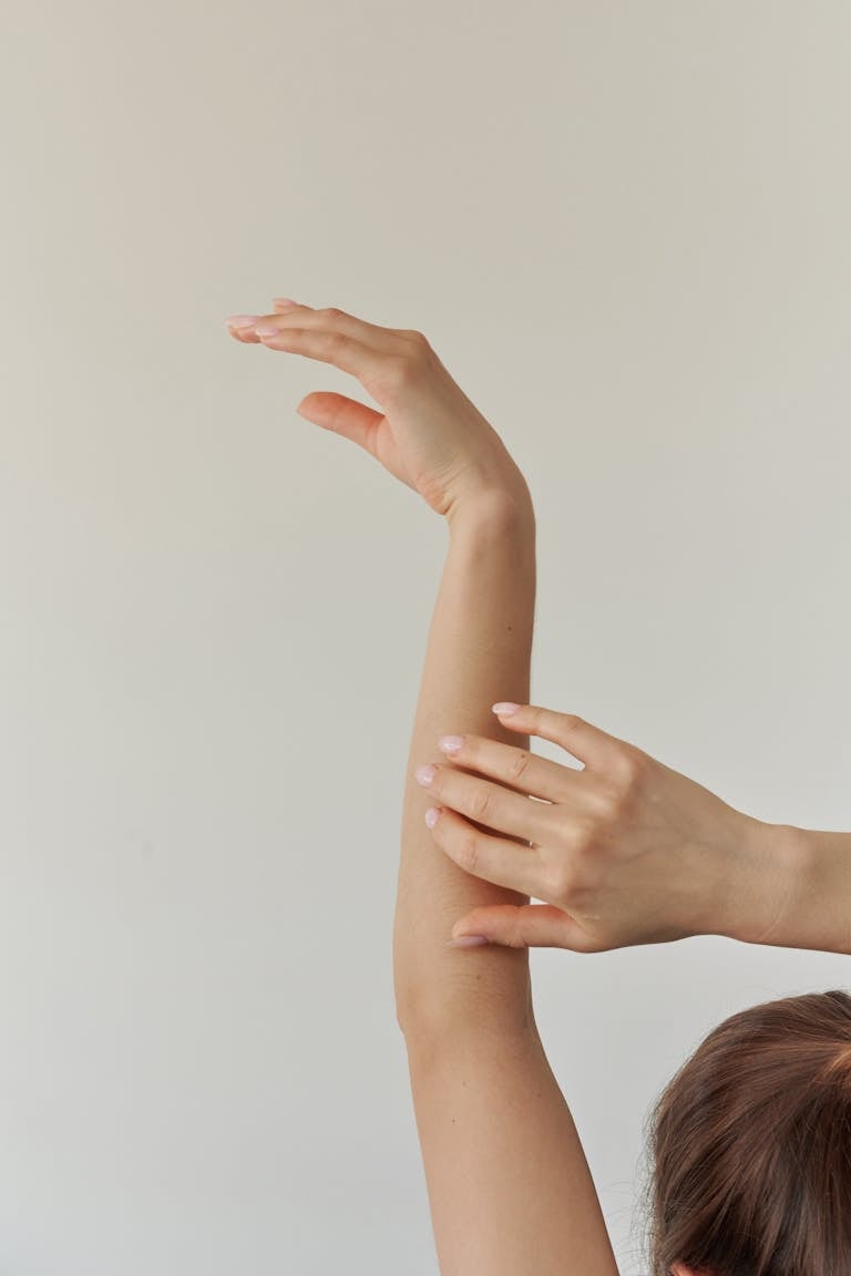 A serene composition featuring a woman's arm gracefully stretched against a neutral background.