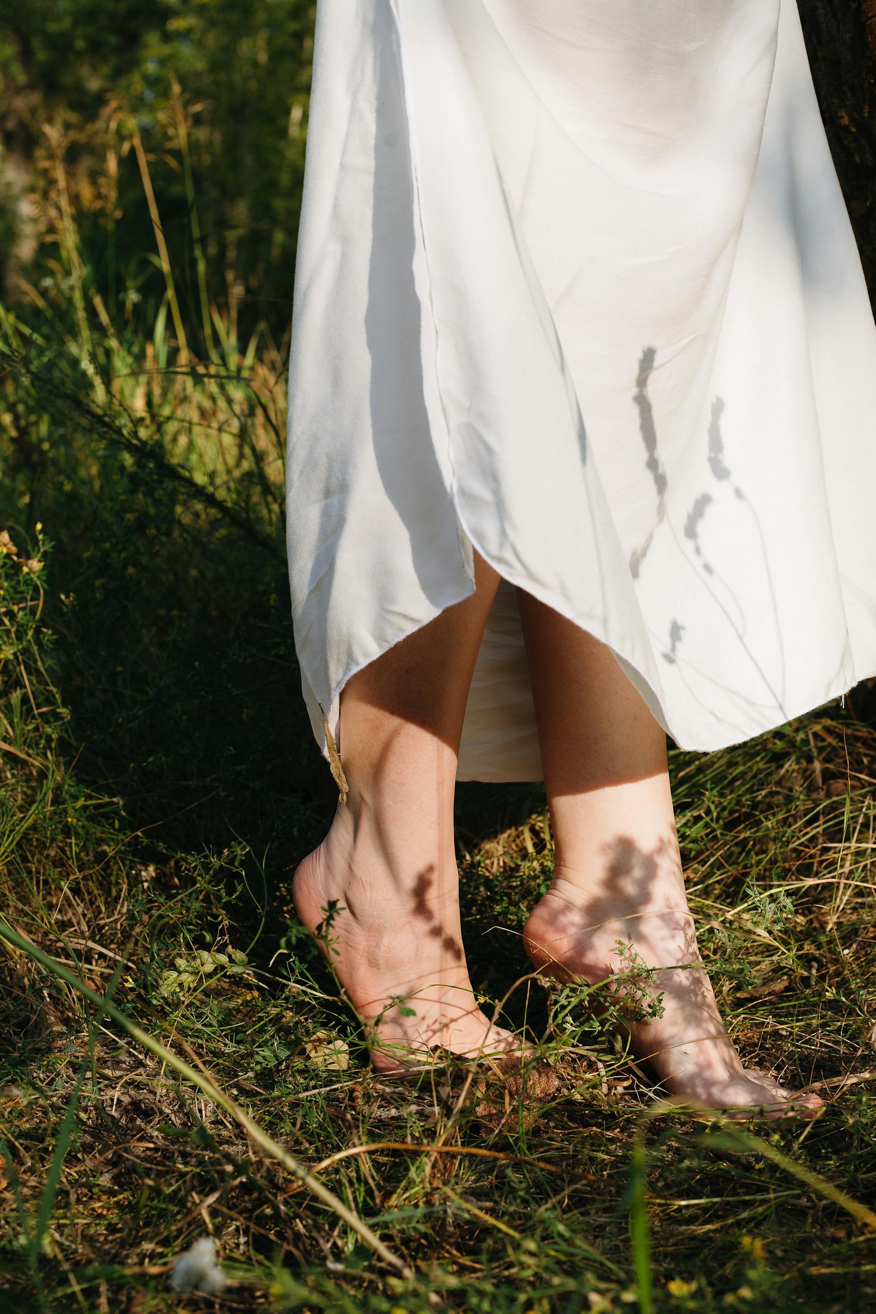 Captivating image of bare feet in a white dress, enjoying nature's serenity.